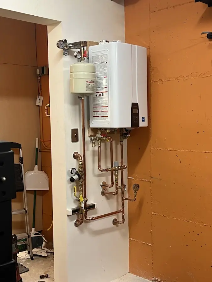 Plumbing technician inspecting water heater connections in Tolono